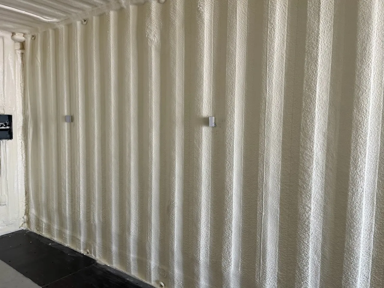 Closed cell foam sprayed on a corrugated steel wall