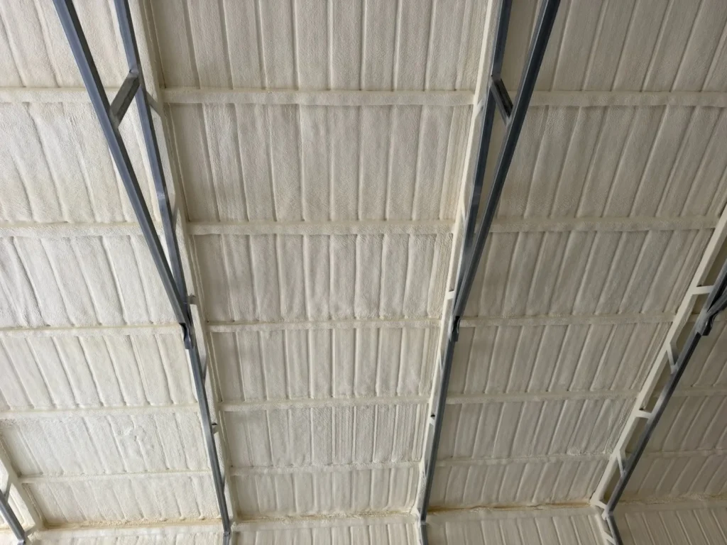 Foam sprayed between purlins on a metal roof deck